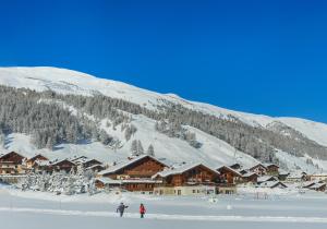 two people skiing in the snow in front of a ski lodge at Hotel Paradiso in Livigno
