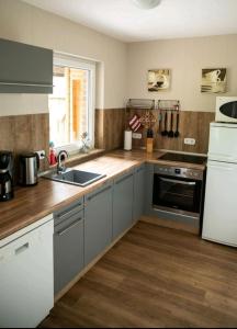 a kitchen with gray cabinets and a sink and a refrigerator at Ferienwohnung Kleine Gasse in Lathen +8 photos