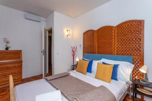 Un dormitorio con una cama grande con almohadas azules y amarillas. en BeGuest Caparica Beach & Surf, en Costa da Caparica