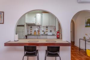 una cocina con un arco sobre un mostrador con taburetes en BeGuest Caparica Beach & Surf, en Costa da Caparica