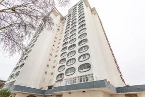 un edificio alto de color blanco con ventanas redondas en BeGuest Caparica Beach & Surf, en Costa da Caparica
