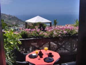 a red table with drinks on a balcony with flowers at Moderne Ferienwohnung mit privatem Balkon sowie Meer- und Gebirgsblick in Icod de los Vinos