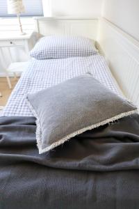 una cama con una almohada gris encima en Ferienhaus Ostseeliebe, en Dahme