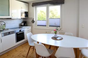 Una cocina blanca con una mesa y sillas blancas. en Ferienhaus Ostseeliebe, en Dahme