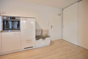 a white kitchen with a microwave on a counter at FeWo Grosse Nr 6 in Kellenhusen +7 photos