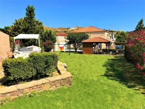 un patio con césped verde y cenador blanco en Marilia & Myronas Lemnos Apartments, en Mirina 77 fotos más