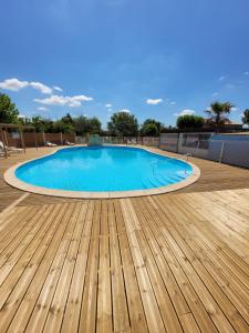 a large swimming pool with a wooden deck at Camping Les Peupliers in Colombiers