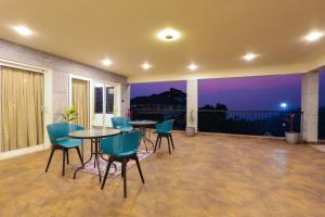 a patio with tables and chairs on a balcony at night at The Cozy Winterfell in Munnar