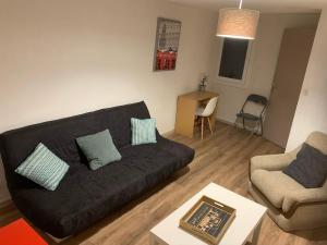 a living room with a black couch and a chair at Seven Keys - Les berges de Ouveze in Le Pouzin