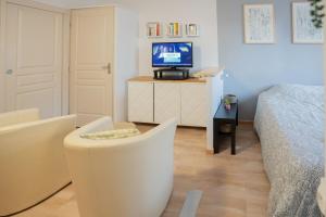 グレウー・レ・バンにあるStudio Coté Jardinのベッドと椅子とテレビのある寝室 +2枚の写真