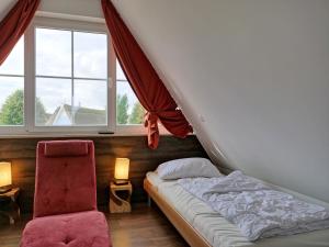 B 4 Reethaus Jaguar mit Sauna und Whirlpool في Gramkow: سرير وكرسي في غرفة مع نوافذ