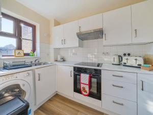 a white kitchen with a stove and a dishwasher at Hersham Apartment Ideal for Work & Relaxation - Pass the Keys in Hersham