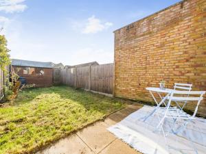 a table and a chair in a yard next to a brick wall at Hersham Apartment Ideal for Work & Relaxation - Pass the Keys in Hersham