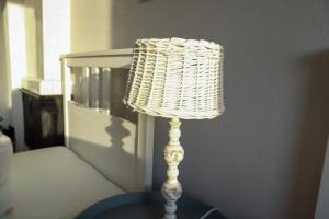 a wicker lamp sitting on a table next to a bed at FeWo Dünenrose in Dahme