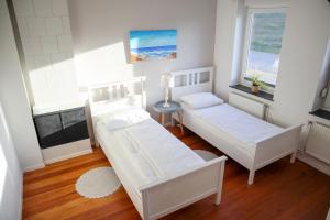 a room with two beds and a table and two windows at FeWo Dünenrose in Dahme