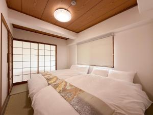 two beds in a room with a window at Residence Yu by b hotel - Quiet & Cozy Apartments Steps from City Center in Hiroshima