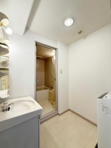 a white bathroom with a sink and a shower at Residence Yu by b hotel - Quiet & Cozy Apartments Steps from City Center in Hiroshima
