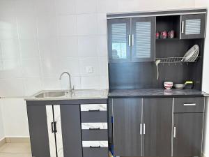 Una cocina con gabinetes grises y un fregadero. en HappySty, en Bayan Lepas 2 fotos más