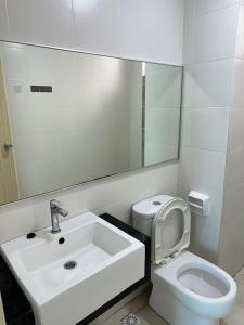 Un baño con lavabo, inodoro y espejo. en HappySty, en Bayan Lepas