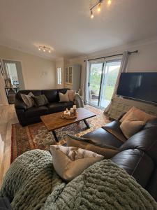 un salon avec un canapé en cuir noir et une table dans l'établissement Green Tree Cottage rural serenity near town, à Mudgee