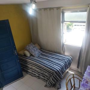 un petit lit dans une chambre avec une fenêtre dans l'établissement Canto doce in Santa Tereza Rio de Janeiro, à Rio de Janeiro