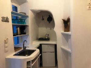 a small white kitchen with a sink and shelves at Milos Heritage Home 1883 in Adamantas