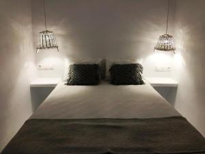 a bed with two pillows in a room with two lights at Milos Heritage Home 1883 in Adamantas