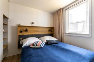 a bedroom with a blue bed with two pillows at Muschel 63 in Gronenberg