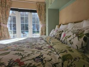 a bedroom with a bed with a floral bedspread and a window at Queen Anne Cottage in Guildford +77 photos
