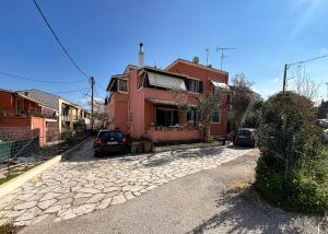 una casa roja con autos estacionados frente a ella en Amy Apartments, en Kassiopi
