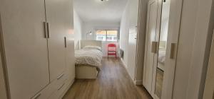 a small bedroom with a bed and a red chair at Apartamento Magdalena II in Ferrol