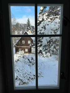 a window looking out at a snow covered house at Kouzelná chalupa u lesa in Česká Lípa