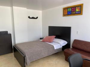 a small bedroom with a bed and a chair at HOTEL Destino Nómada Calle 11 n 1-38 in Bogotá