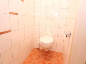 a bathroom with a toilet in a white tiled room at Large Apartment in Maria Alm with Terrace in Maria Alm am Steinernen Meer