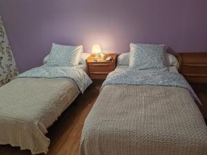 Un dormitorio con dos camas y una mesa con lámpara. en GITE Chez Marilou, en Aulnay-sous-Bois