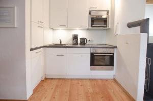 a kitchen with white appliances and a wooden floor at Haus Schünemann 4 in Kellenhusen