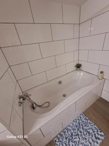a white bath tub in a bathroom with a rug at Camelia's Unterkunft in Sulzthal +20 photos