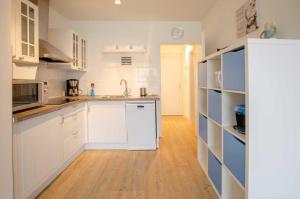 una cucina con mobili bianchi e pavimento in legno di FeWo Heimathafen a Kellenhusen