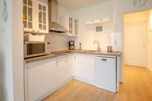 una cucina bianca con mobili bianchi e un lavello di FeWo Heimathafen a Kellenhusen