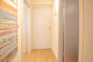 un corridoio con porta bianca e pavimento in legno di FeWo Heimathafen a Kellenhusen