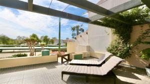 eine Terrasse mit zwei weißen Bänken und einem Gebäude in der Unterkunft Vilar Do Jardim 49 - CD 209, Cleverdetails in Vilamoura