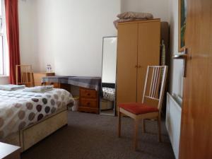 a bedroom with a bed and a chair and a mirror at Malone Townhouse in Belfast