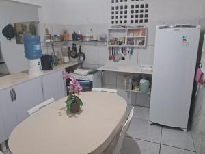 a white kitchen with a table and a refrigerator at Kasa Morro Branco in Beberibe