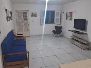 a living room with a tv and a blue chair at Kasa Morro Branco in Beberibe