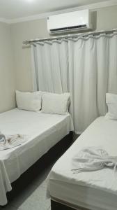 two beds in a room with white curtains at Casa de Temporada Maria Rosa in Piranhas +18 photos