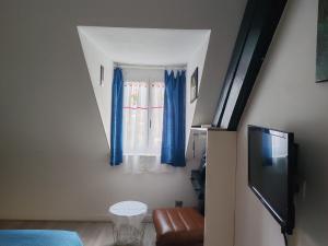 Habitación con una ventana con cortinas azules en GITE Chez Marilou, en Aulnay-sous-Bois 7 fotos más