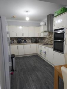 a kitchen with white cabinets and black appliances at Lux Home in Dagenham