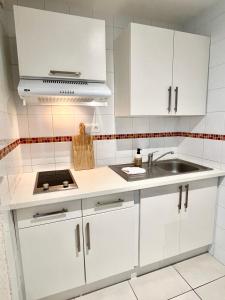 Una cocina con gabinetes blancos y un fregadero. en La Côtière, Terrasse et Jardin RDC, Proche plage, en Saint-Palais-sur-Mer