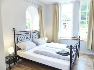 a bedroom with a black and white bed with two windows at Ferienwohnung Sonnenstrahl in Walsrode