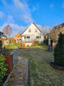 a white house with a fence in the yard at Kapitänshaus - Wolkenstube in Barth